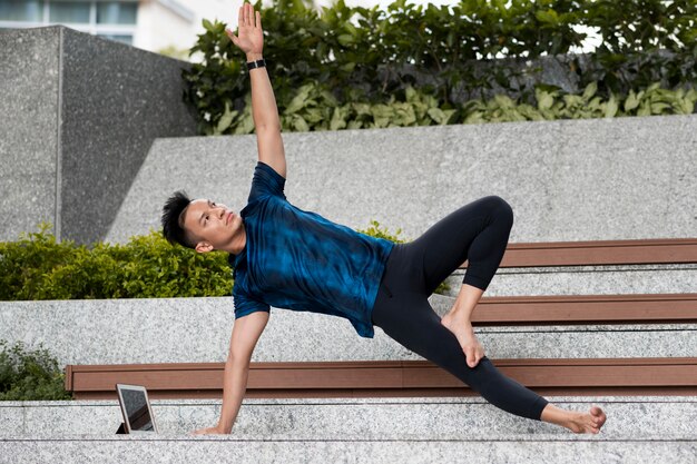 Mann, der Yoga auf Stufen im Freien tut