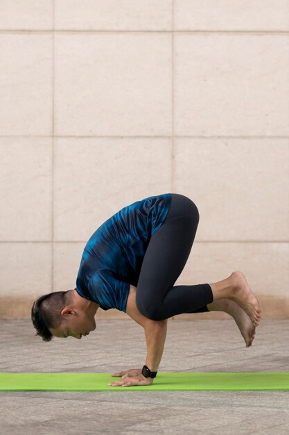 Mann, der Yoga draußen auf Matte praktiziert