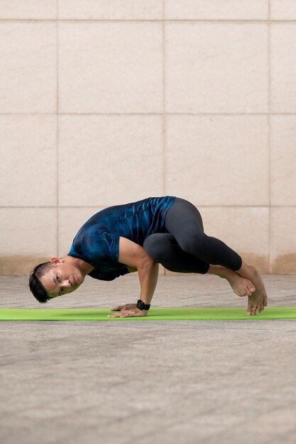 Mann, der Yoga draußen auf Matte tut