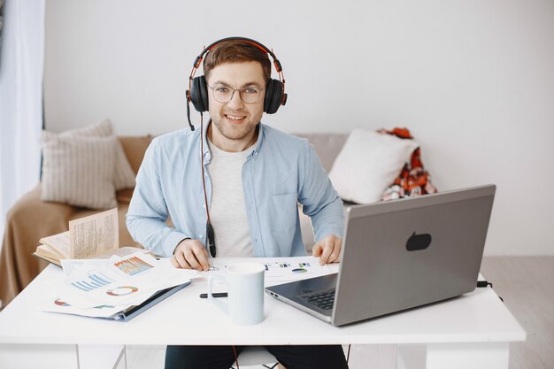 Mann, der zu Hause im Wohnzimmer sitzt. Guy genießt das Lernen mit Laptop und Headset.