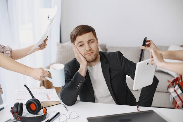 Mann, der zu Hause im Wohnzimmer sitzt. Trauriger Mann müde von der Arbeit.