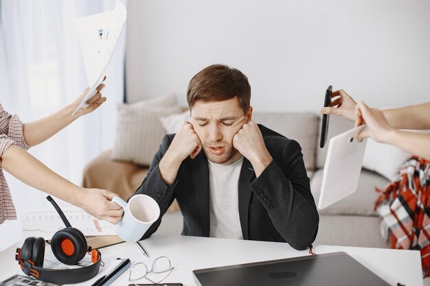 Mann, der zu Hause im Wohnzimmer sitzt. Trauriger Mann müde von der Arbeit.