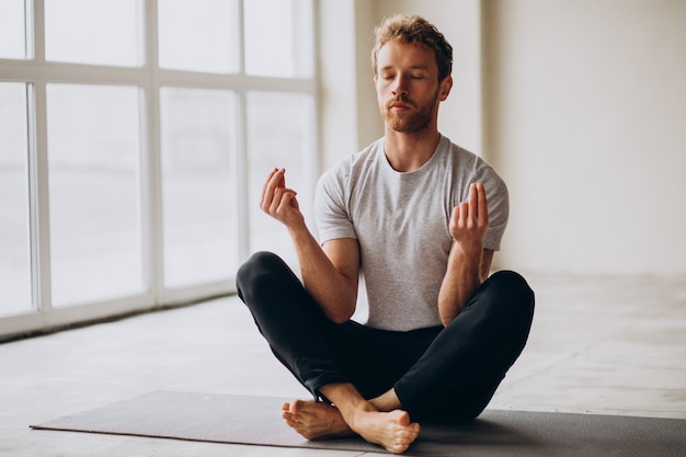 Kostenloses Foto mann, der zu hause yoga auf der matte praktiziert