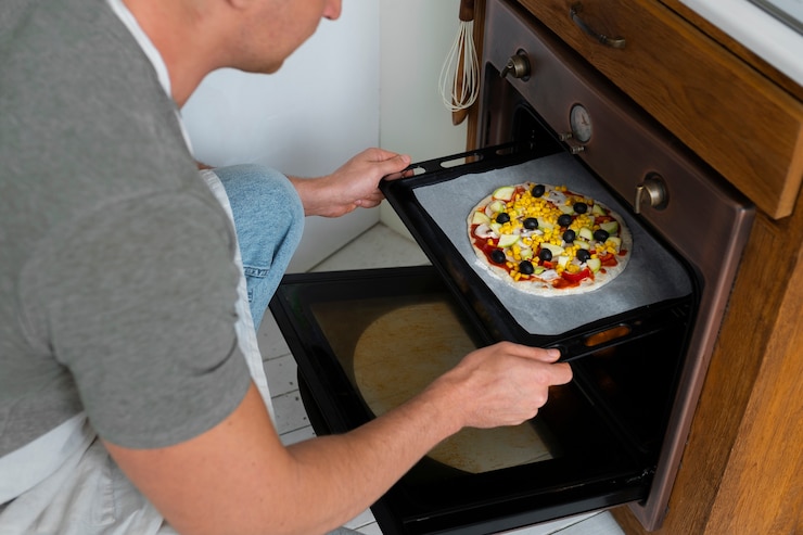 Kostenlose Foto mann des hohen winkels, der pizza kocht