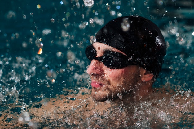 Mann des hohen Winkels mit Schutzbrillen und Kappenschwimmen