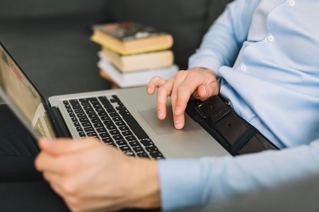 Mann des Kropfbaums, der Laptop auf Couch durchstöbert