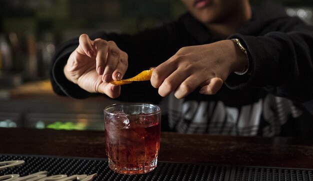 Mann drückt in einer Bar eine Zitrone auf seinen Whiskey