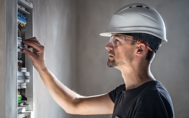 Kostenloses Foto mann, ein elektrotechniker, der in einer schalttafel mit sicherungen arbeitet.