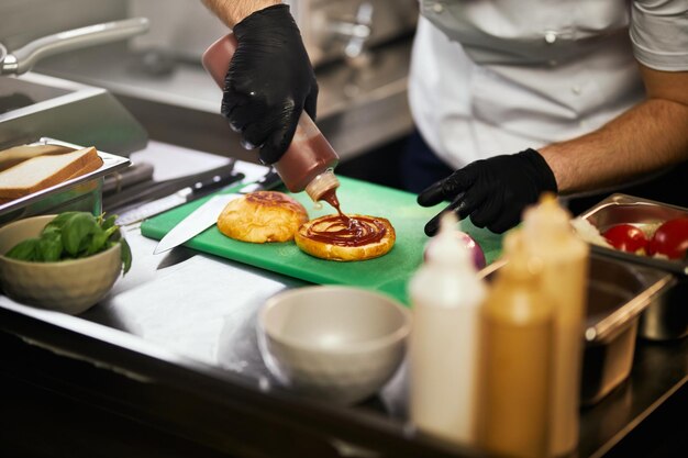 Mann gießt Ketchup auf Burgerbrötchen