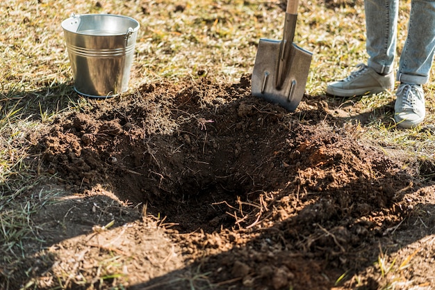 Mann gräbt ein Loch mit Schaufel, um einen Baum zu pflanzen