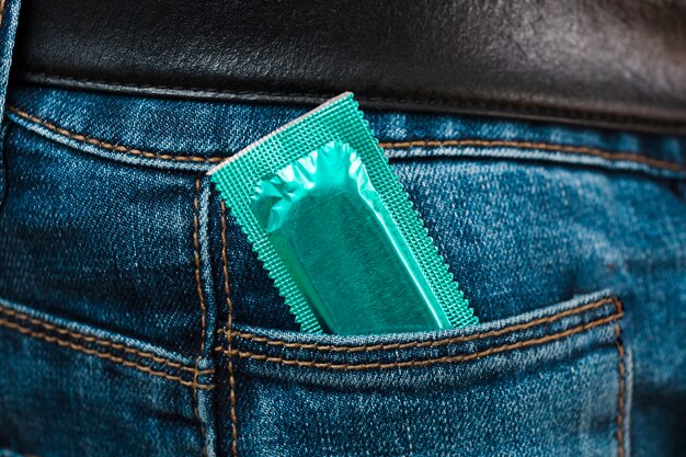 Mann hält ein Kondom in der Tasche