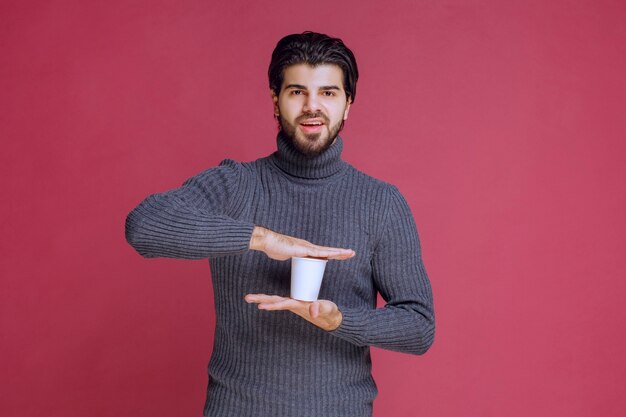 Mann hält eine Einwegkaffeetasse in der Hand und fühlt sich positiv.