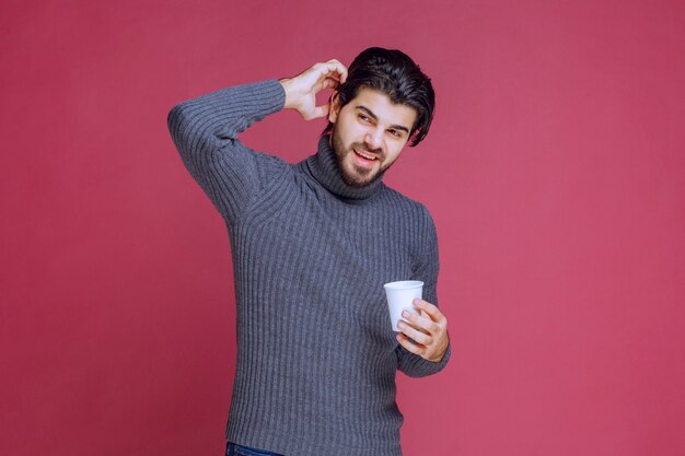 Mann hält eine Einwegkaffeetasse in der Hand und fühlt sich positiv.