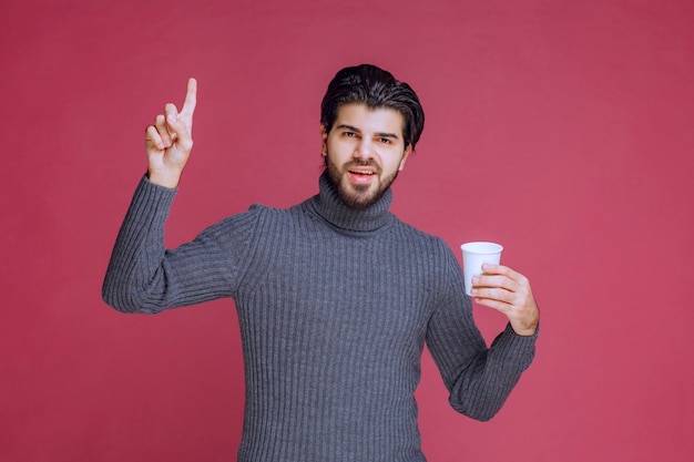 Mann hält eine Einwegkaffeetasse und fühlt sich kraftvoll und energisch.