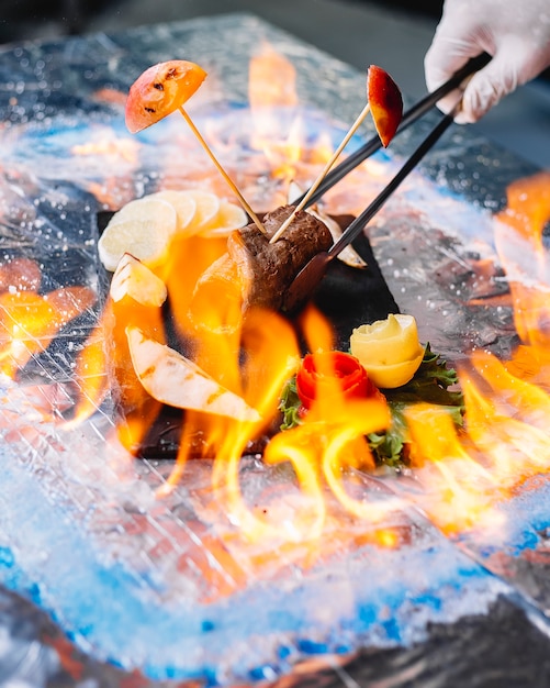 Kostenloses Foto mann hält gegrillte fleischrolle mit birnengrün und dem glas wein seitenansicht