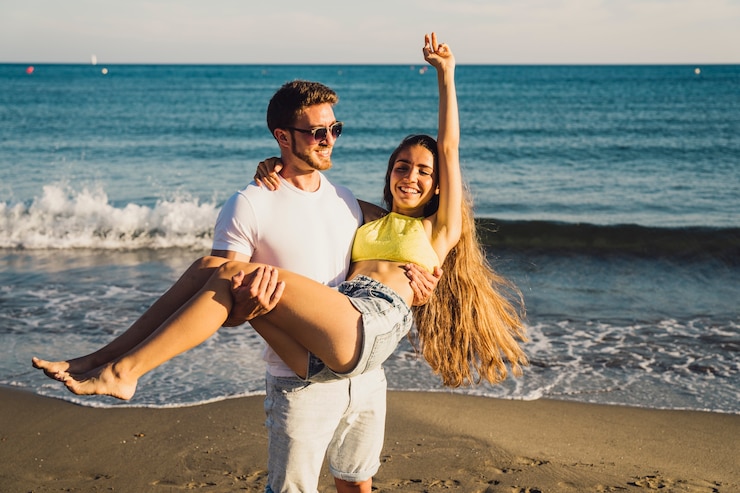 Kostenlose Foto mann hält seine freundin am strand