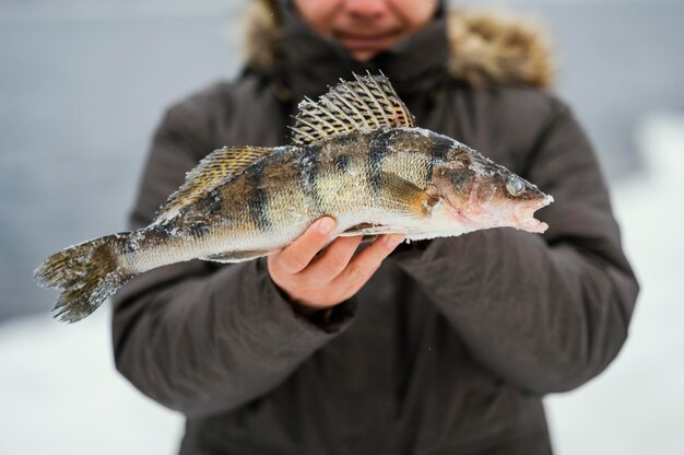 Mann hält siegreich einen Fisch, den er gefangen hat