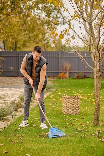 Kostenloses Foto mann harkt blätter auf rasen im garten