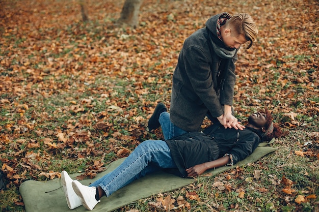 Mann hilft einer Frau. Afrikanisches Mädchen liegt bewusstlos. Erste Hilfe im Park leisten.