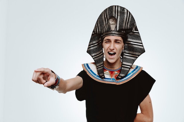 Mann im alten ägyptischen Kostüm verrückt glücklich lachend mit Zeigefinger auf etwas auf Weiß zeigend