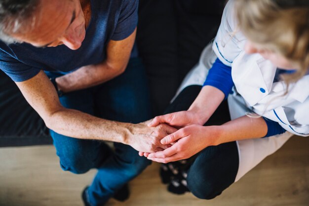 Mann im Altershaus, das Hand der Krankenschwester hält