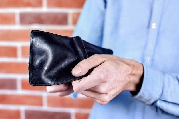 Mann im blauen Hemd, das schwarze leere Brieftasche zeigt