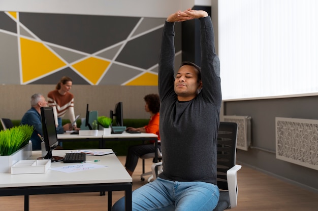 Kostenloses Foto mann im büro, der sich während eines arbeitstages dehnt