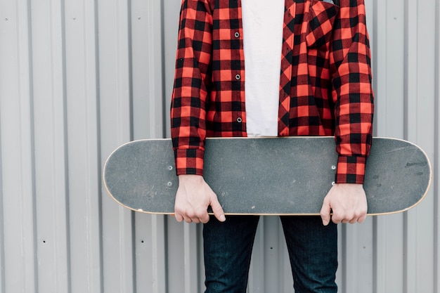 Kostenloses Foto mann im flanellhemd, das skateboard hält