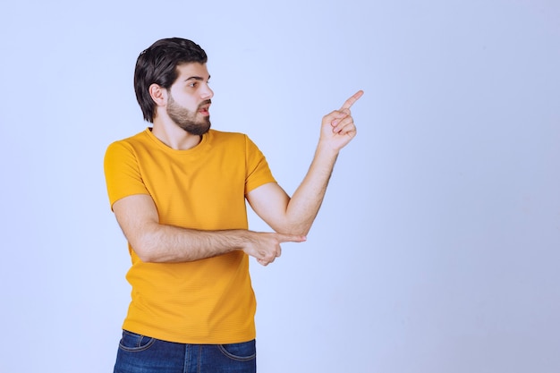 Mann im gelben Hemd, das etwas rechts zeigt.