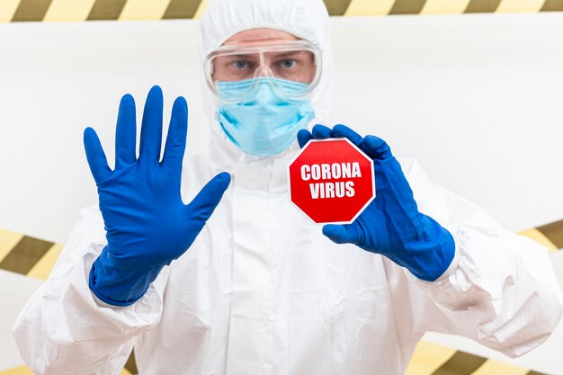 Mann im Hazmat-Anzug mit Coronavirus-Stoppschild