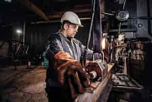 Kostenloses Foto mann im helm bewegt ein stück schiene in der metallfabrik.