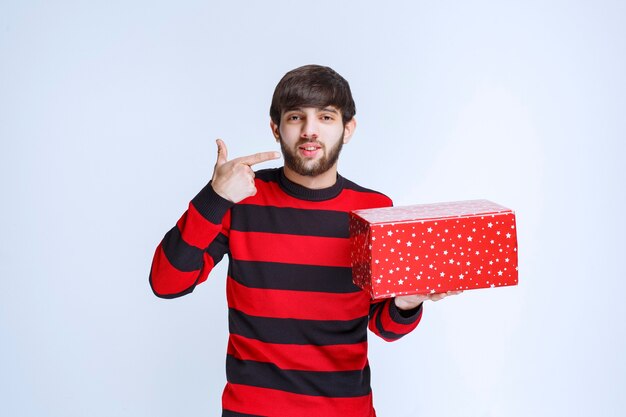 Mann im rot gestreiften Hemd mit roter Geschenkbox und ruft jemanden an, um ihn zu präsentieren.
