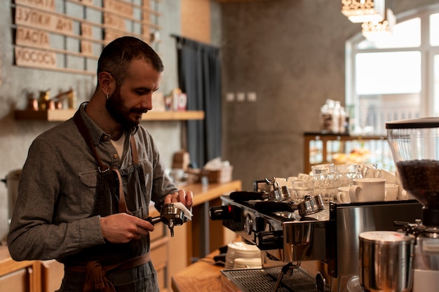 Mann im Schutzblech, das Kaffee an der Maschine zubereitet