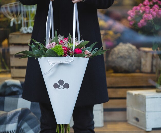 Mann im Schwarzen, das einen Weißbuchblumenstrauß von Mischblumen durchlöchert.