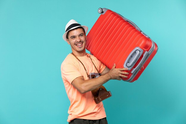 Mann im Urlaub mit großen roten Koffer auf Blau