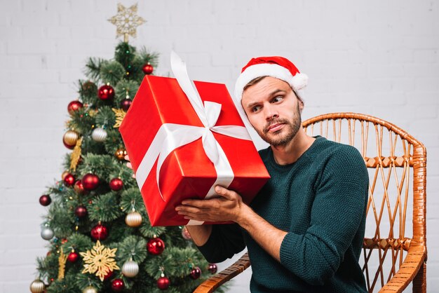 Mann im Weihnachtshut, der Geschenkbox hält