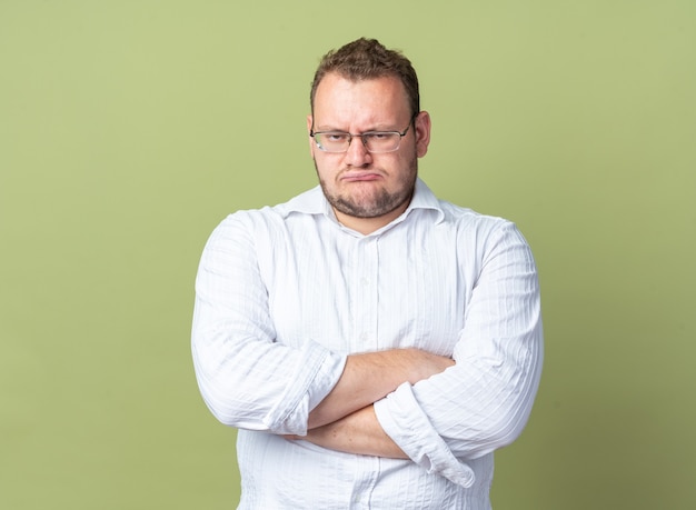 Mann im weißen Hemd mit Brille mit gerunzelter Stirn und verschränkten Armen