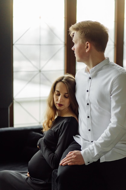 Mann im weißen Hemd und Frau im schwarzen Kleid Schwangerschaftsfoto