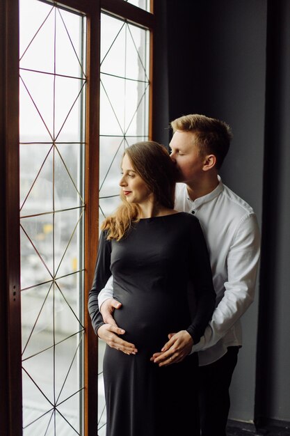 Mann im weißen Hemd und Frau im schwarzen Kleid Schwangerschaftsfoto