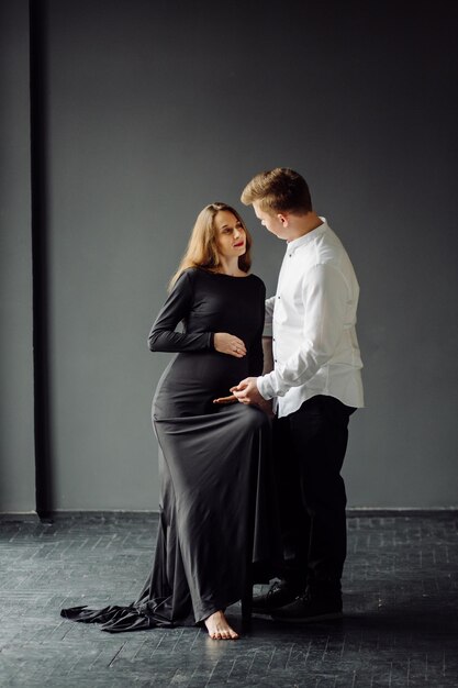 Mann im weißen Hemd und Frau im schwarzen Kleid Schwangerschaftsfoto