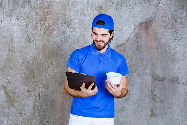 Mann in blauer Uniform, der einen Plastikbecher zum Mitnehmen hält und den Kundennamen liest.