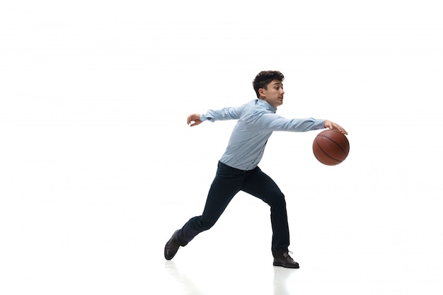 Mann in Bürokleidung, die Basketball auf weißem Raum spielt. Ungewöhnlicher Blick für Geschäftsmann in Bewegung, Aktion. Sport, gesunder Lebensstil.