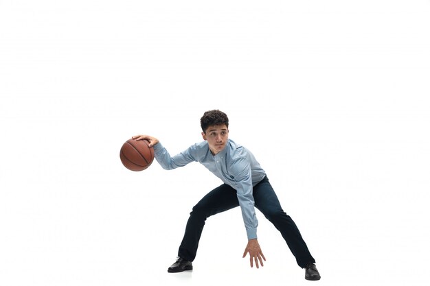 Mann in Bürokleidung, die Basketball auf weißem Raum spielt. Ungewöhnlicher Blick für Geschäftsmann in Bewegung, Aktion. Sport, gesunder Lebensstil.