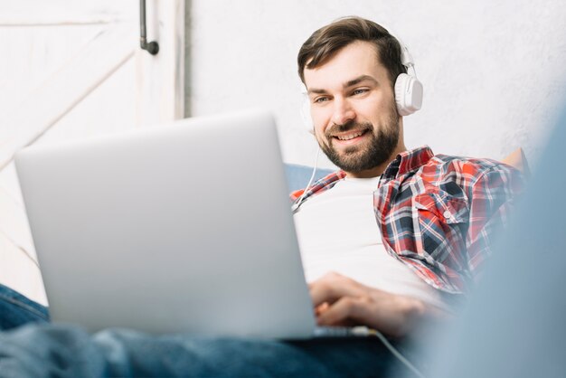 Mann in den Kopfhörern, die Laptop verwenden