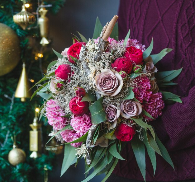 Mann in den Winterausstattungen mit einem Blumenstrauß von Mischblumen