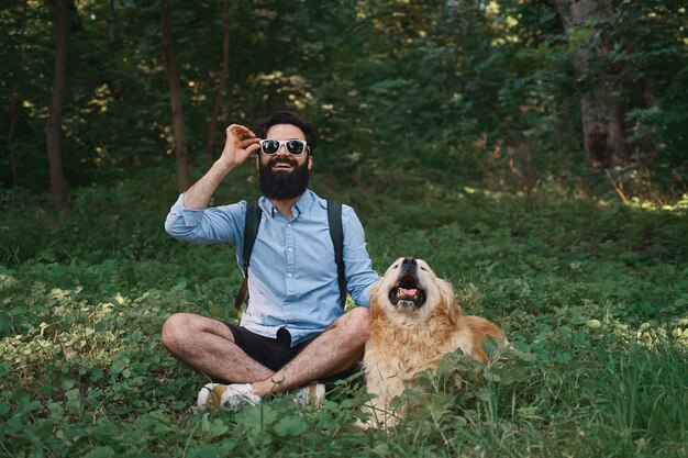 Mann in der Freizeitkleidung und sein Hund, der auf Kamera schaut