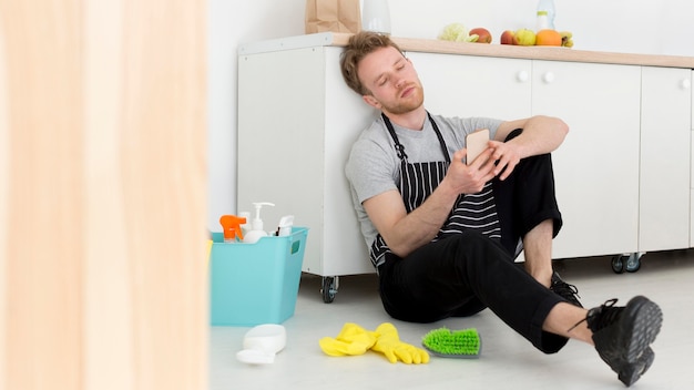 Mann in der Pause von der Reinigung Überprüfung Handy