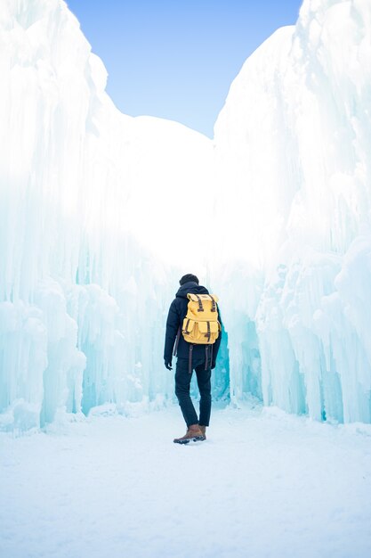 Mann in der schwarzen Jacke und in den blauen Jeans, die auf schneebedecktem Boden stehen