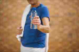 Kostenloses Foto mann in der turnhalle, die wasserflasche zeigt