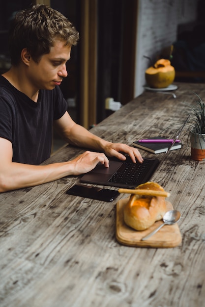 Mann in einem Café mit einem Laptop arbeiten, Essen, Arbeiten, Smartphone
